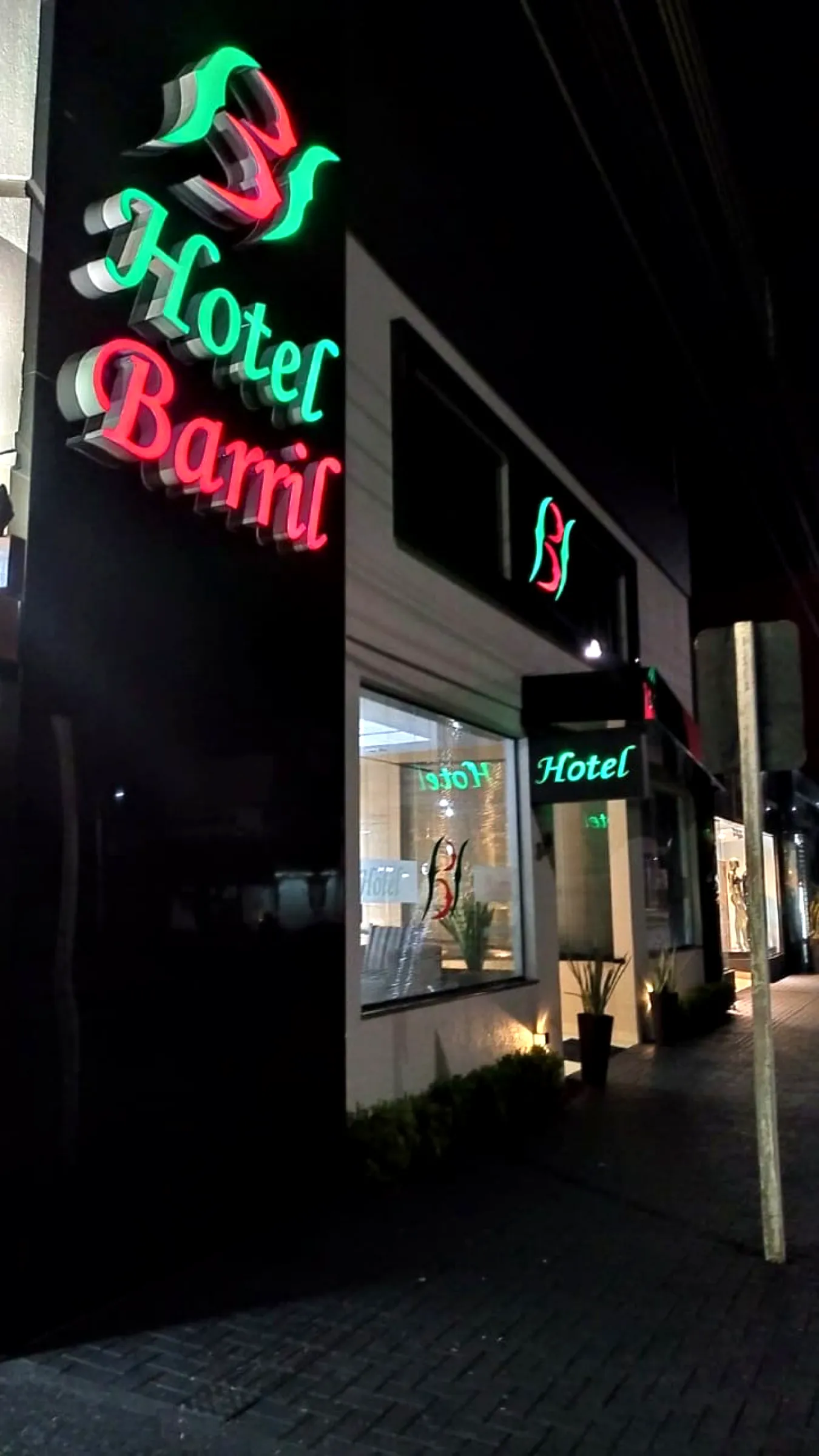 Fachada noturna do Hotel Barril com letreiro luminoso na Avenida Cuiabá